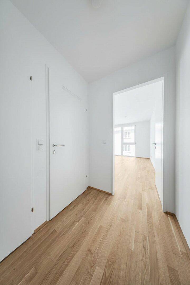 Heller Flur mit Parkettboden und weißen Türen, der zu den angrenzenden Räumen führt.