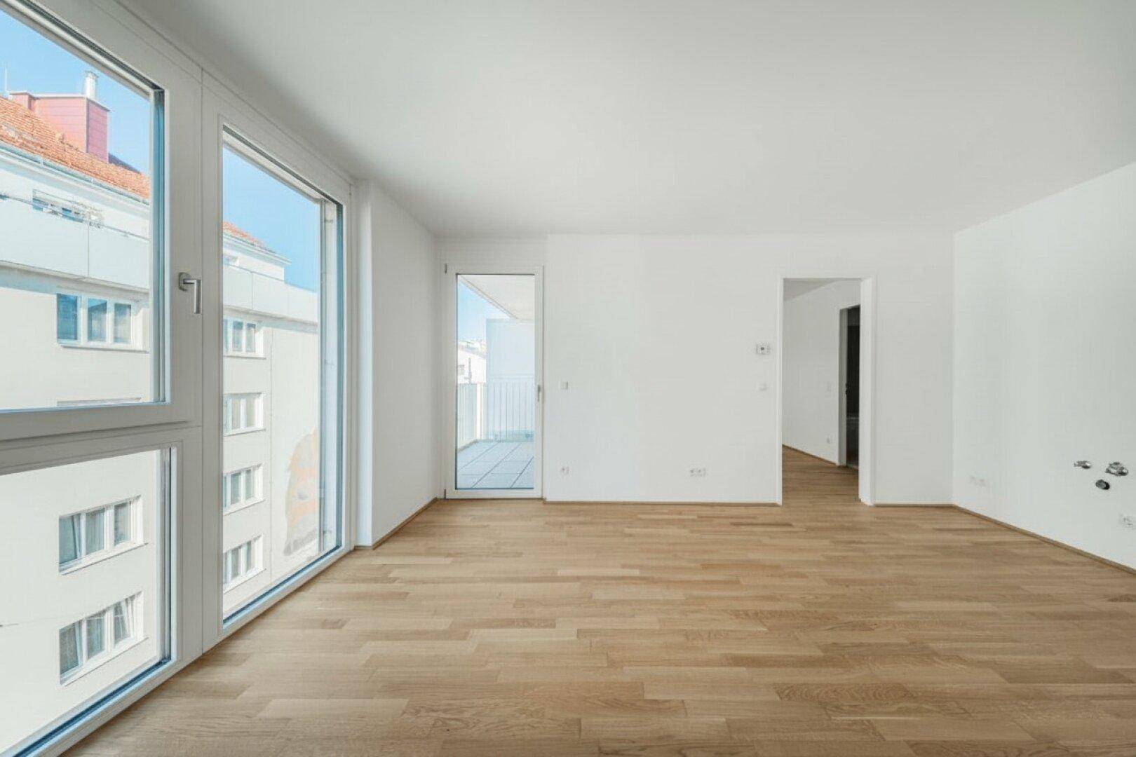 Heller, leerer Raum mit großen Fenstern und Zugang zu einem Balkon, ideal für Wohnzwecke.