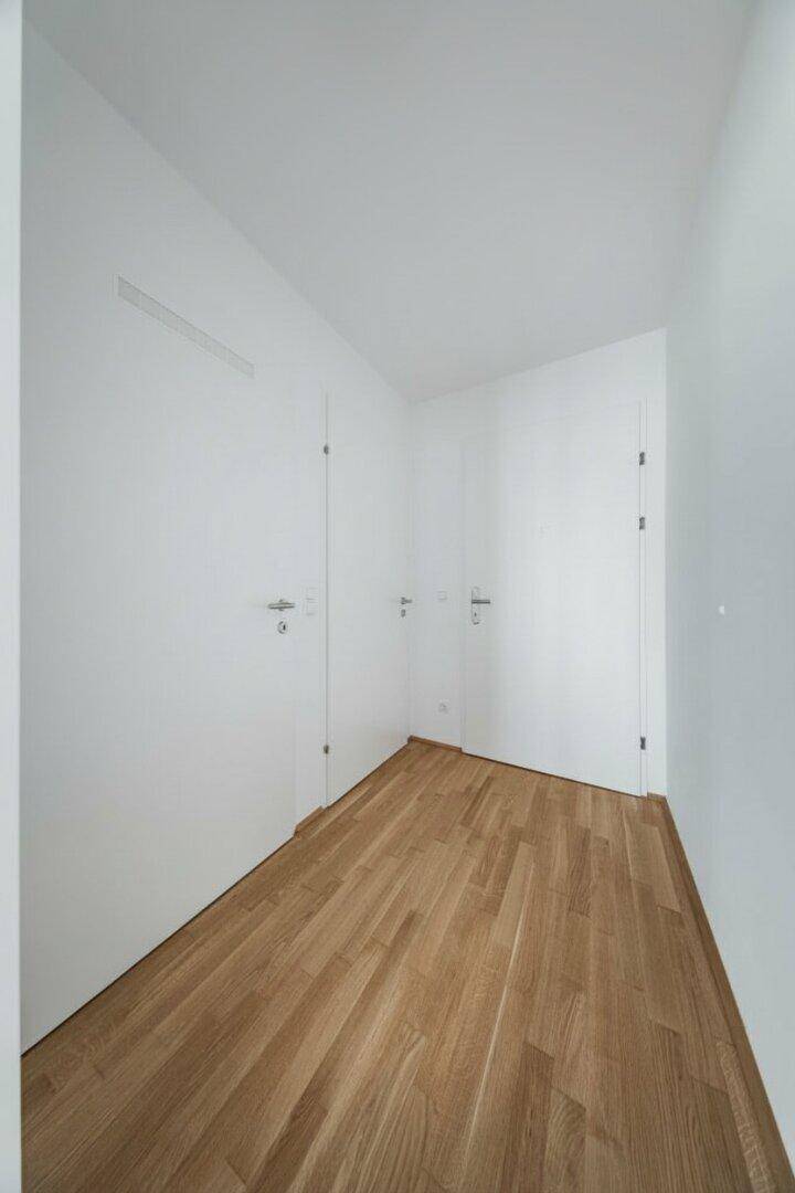 Heller Flur mit Holzboden und mehreren Türen, verbindet verschiedene Räume der Wohnung.