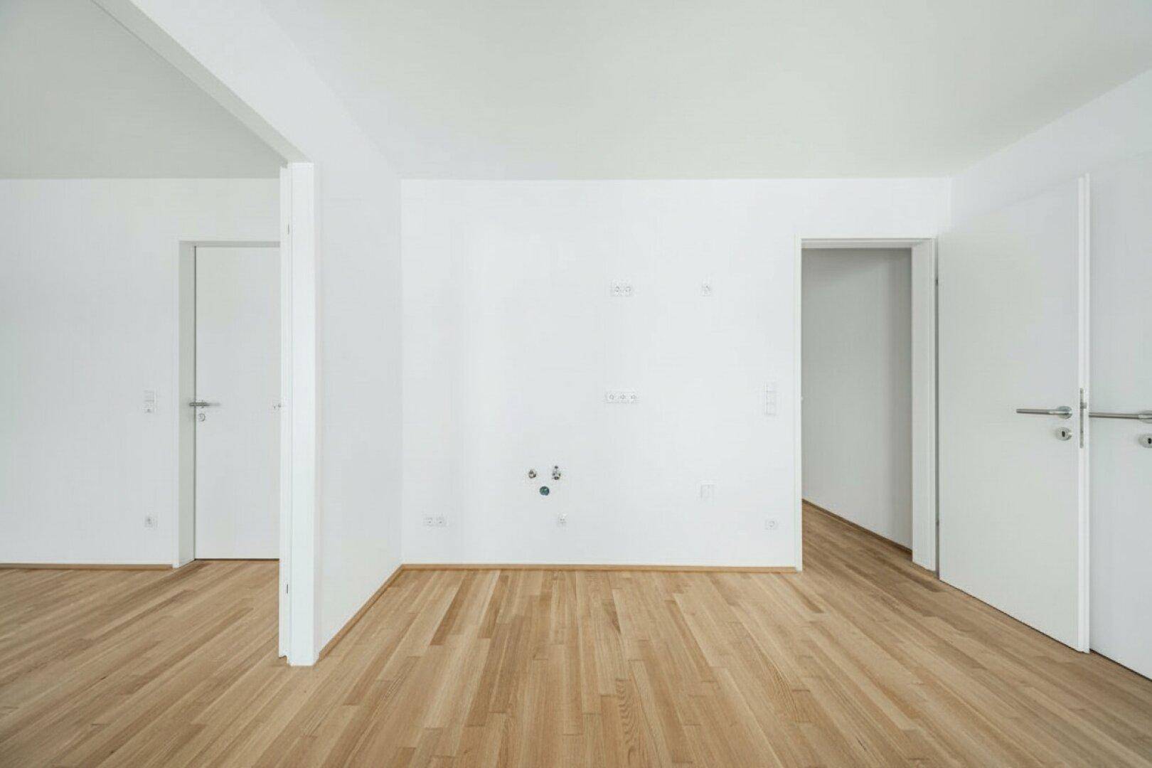 Leerer Raum mit Anschlüssen an der Wand, bietet flexible Nutzungsmöglichkeiten für Küche oder Wohnbereich.