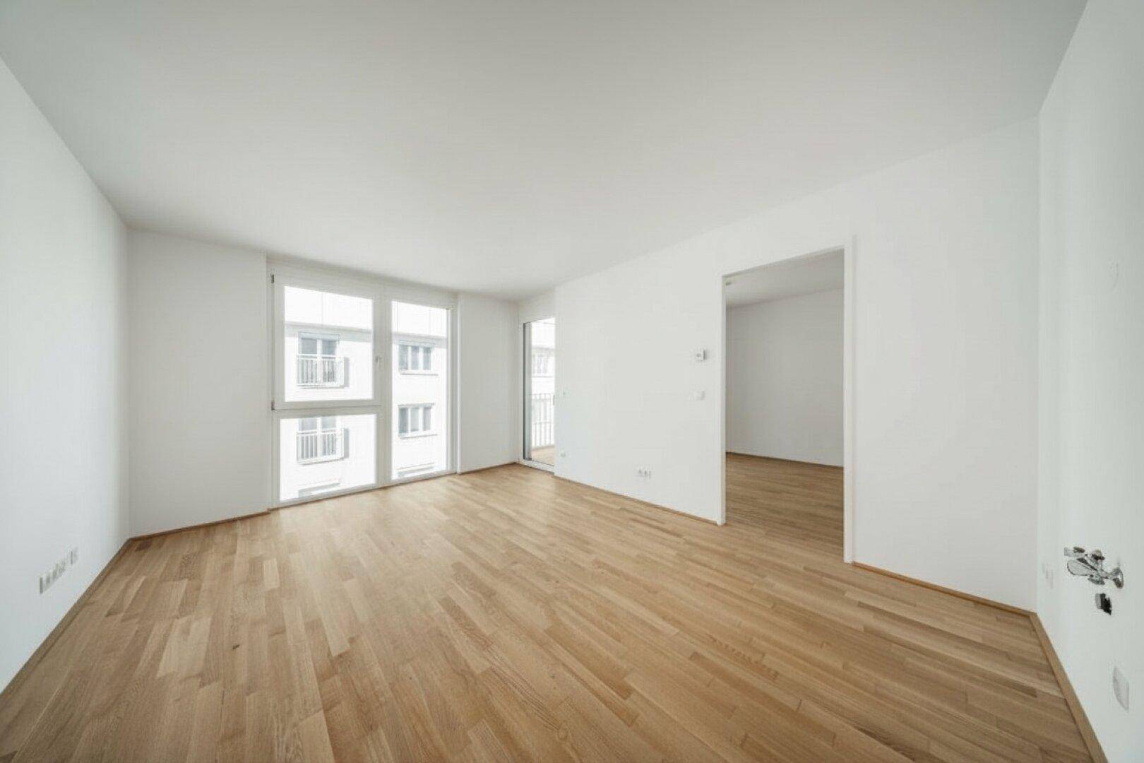 Großer, heller Raum mit breiten Fenstern und Balkonzugang, ideal für einen offenen Wohnbereich.
