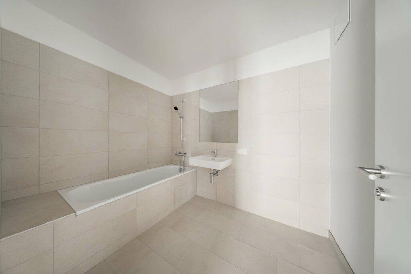 Modernes Badezimmer mit integrierter Badewanne und Einzelwaschbecken, hell gefliest.