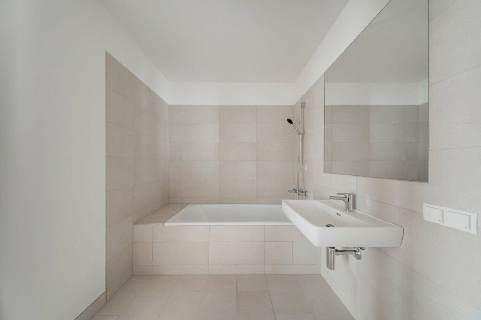 Zeitgemäßes Badezimmer mit Badewanne und elegantem Waschbecken, ausgestattet mit großem Spiegel.