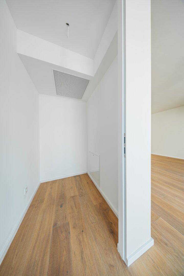 Kleiner, heller Abstellraum mit Holzboden und weißen Wänden, ideal für zusätzlichen Stauraum.