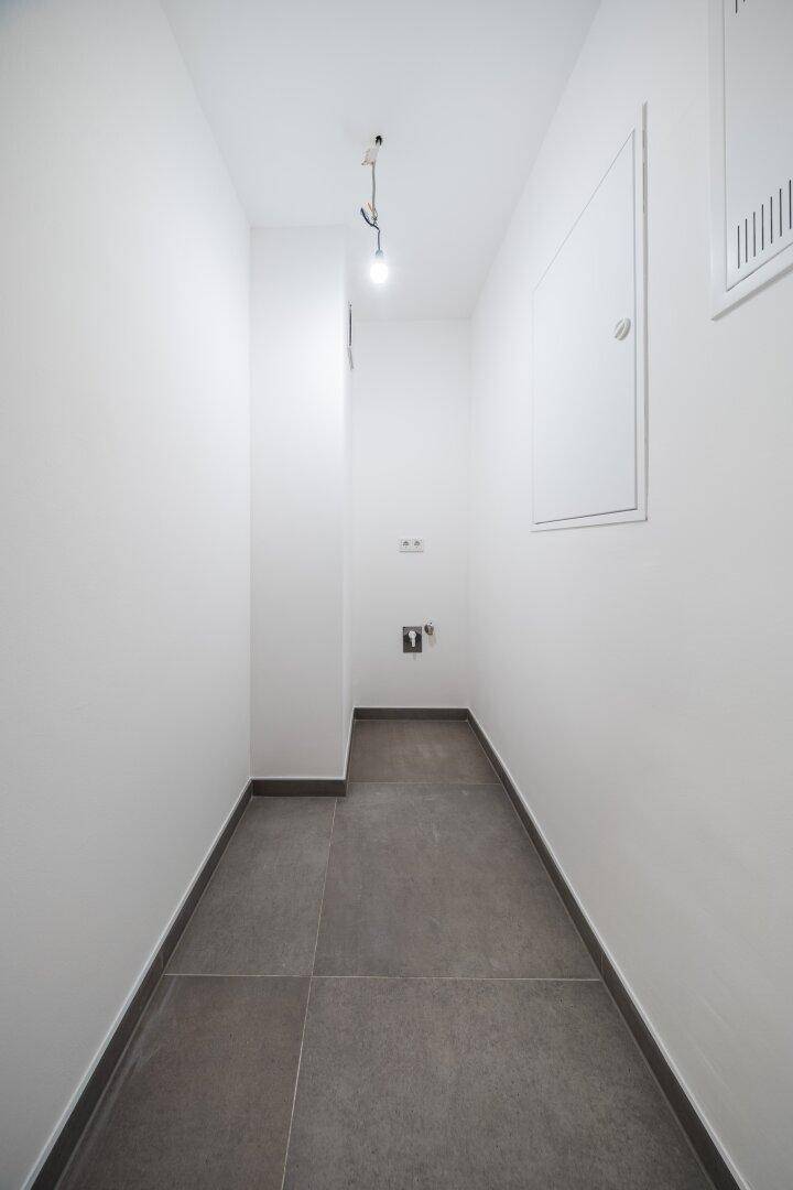 Praktischer Abstellraum mit Fliesenboden und weiß gestrichenen Wänden, ideal für Lagerzwecke.