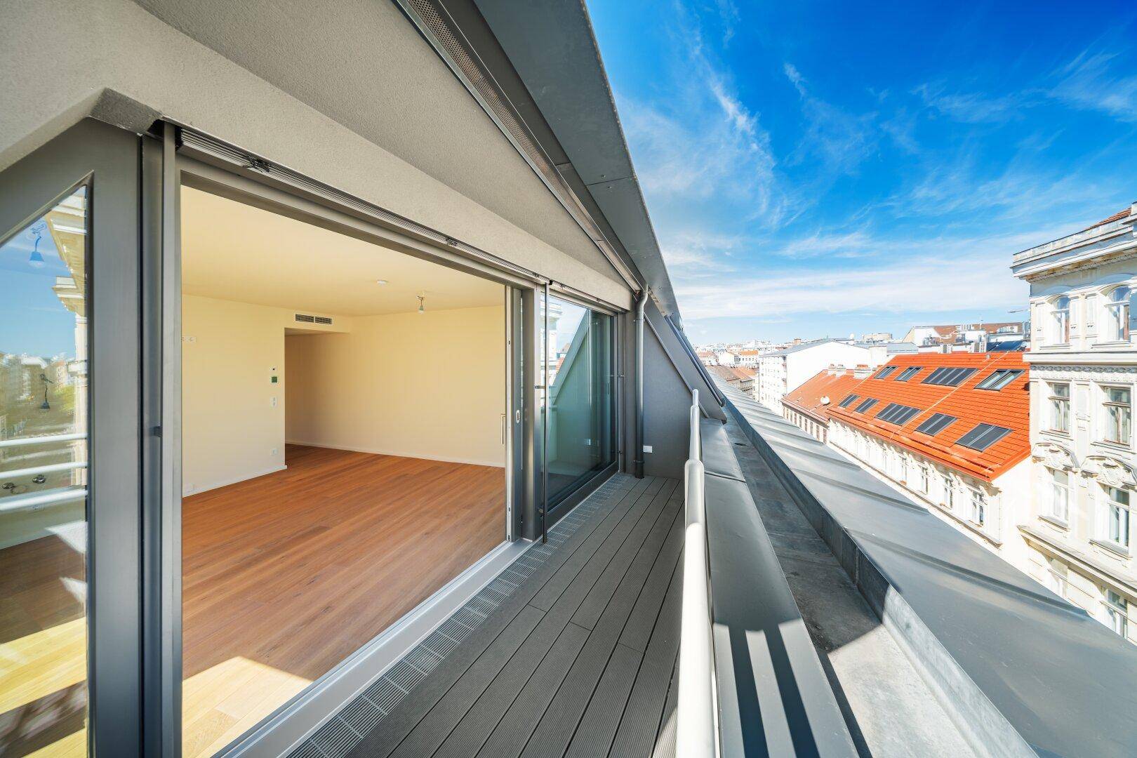 Geräumige Terrasse mit Blick über die Dächer der Stadt und Zugang zu einem hellen Innenraum.