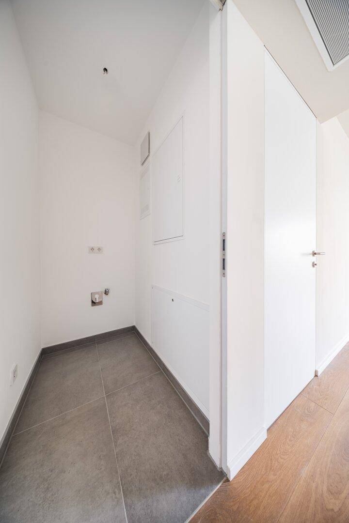 Praktischer Hauswirtschaftsraum mit Fliesenboden und Anschlüssen, ideal für Waschmaschine und Trockner.