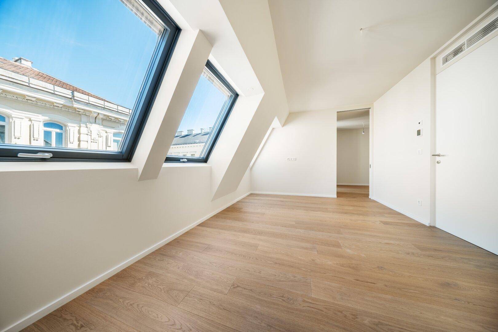 Helles Dachgeschosszimmer mit Holzboden und großen Dachfenstern, bereit zur individuellen Gestaltung.