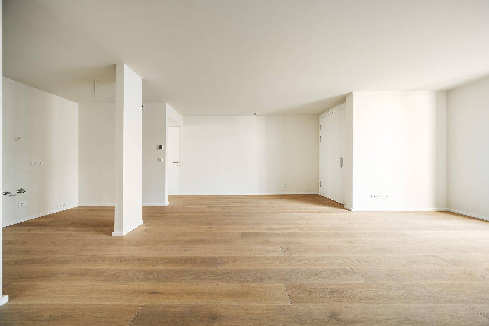 Großer, leerer Raum mit Holzboden und weißen Wänden, ideal für individuelle Einrichtungsideen.
