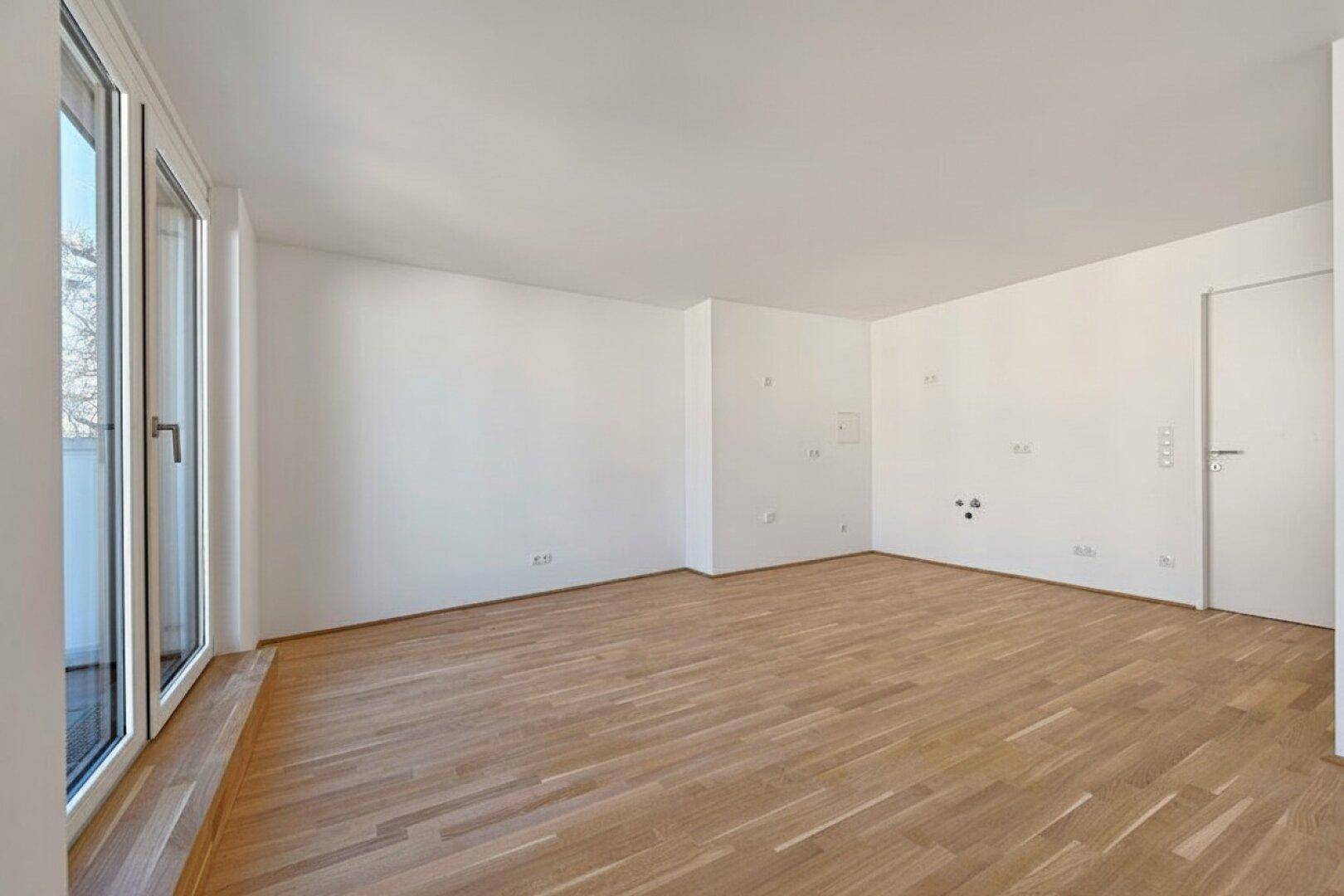 Leeres Zimmer mit Parkettboden und weißen Wänden, bereit für individuelle Gestaltung und Einrichtung.