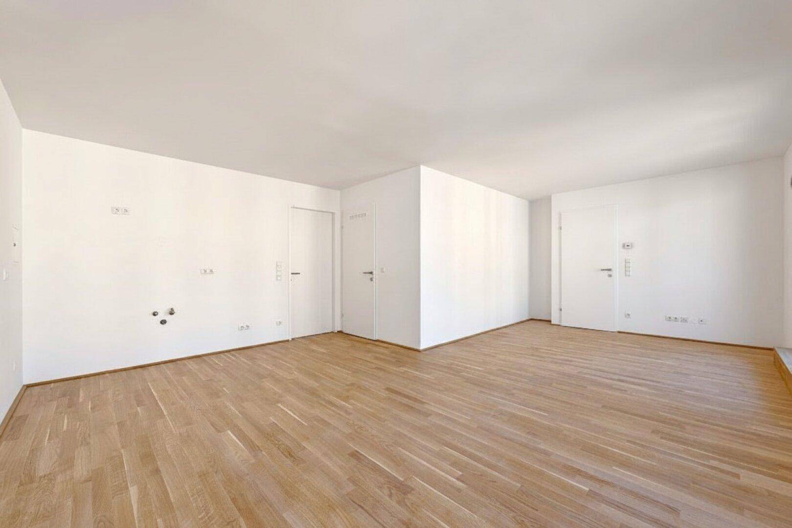 Großes, leeres Zimmer mit Parkettboden und mehreren Türen, bietet vielseitige Nutzungsmöglichkeiten.