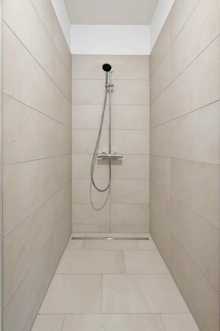 Begehbare Dusche mit beigefarbenen Fliesen und moderner Regendusche für entspannende Momente.
