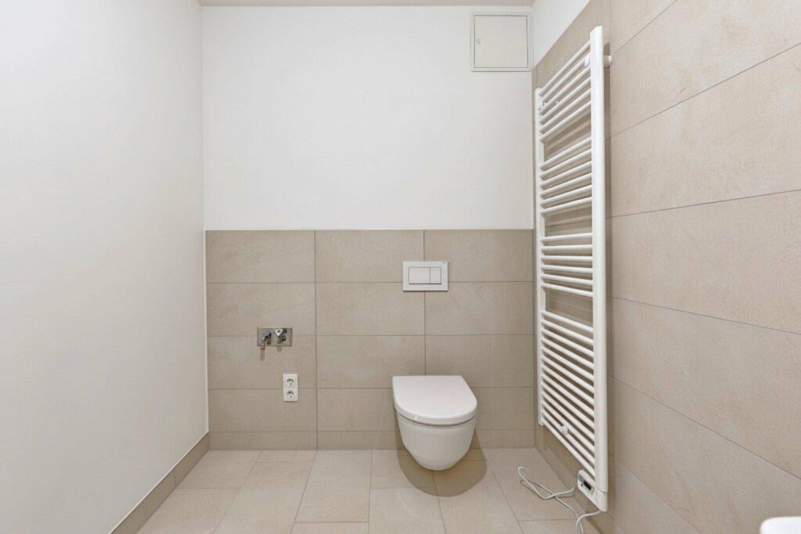 Helles Gäste-WC mit wandhängender Toilette, beigefarbenen Fliesen und praktischem Handtuchheizkörper.