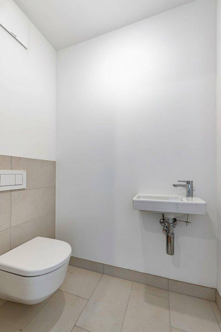 Kleines WC mit wandhängender Toilette und kompaktem Waschbecken, in hellen Farben gehalten.