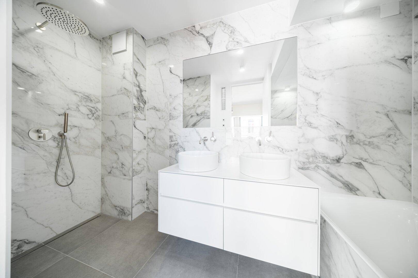 Modernes Badezimmer mit Marmorfliesen, Doppelwaschbecken und großer Regendusche.