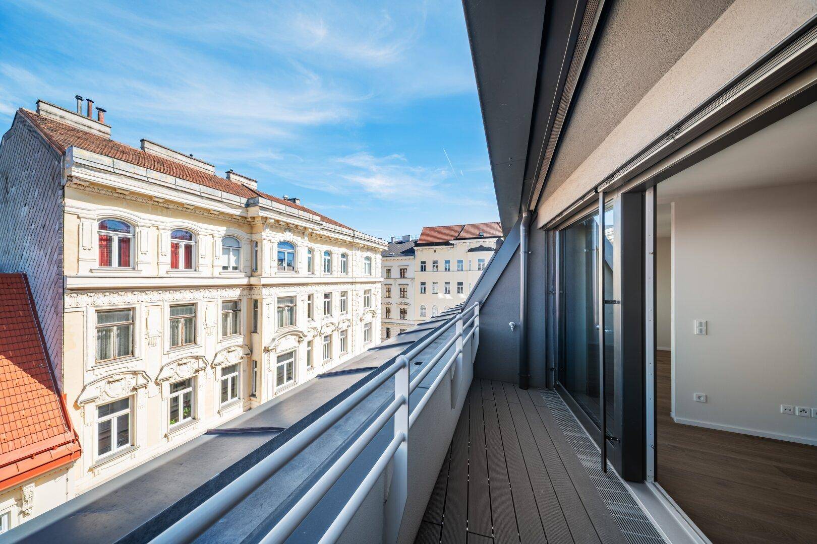 Langer Balkon mit Blick auf die historische Stadtarchitektur und rote Dächer.