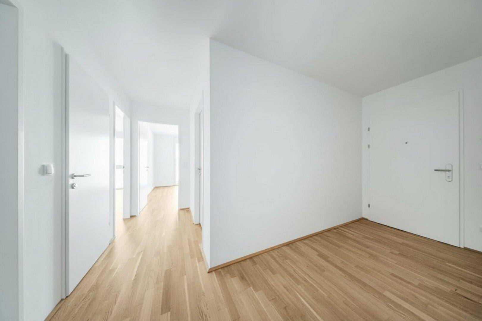 Heller Flur mit Holzboden und mehreren weißen Türen, der zu verschiedenen Räumen führt.