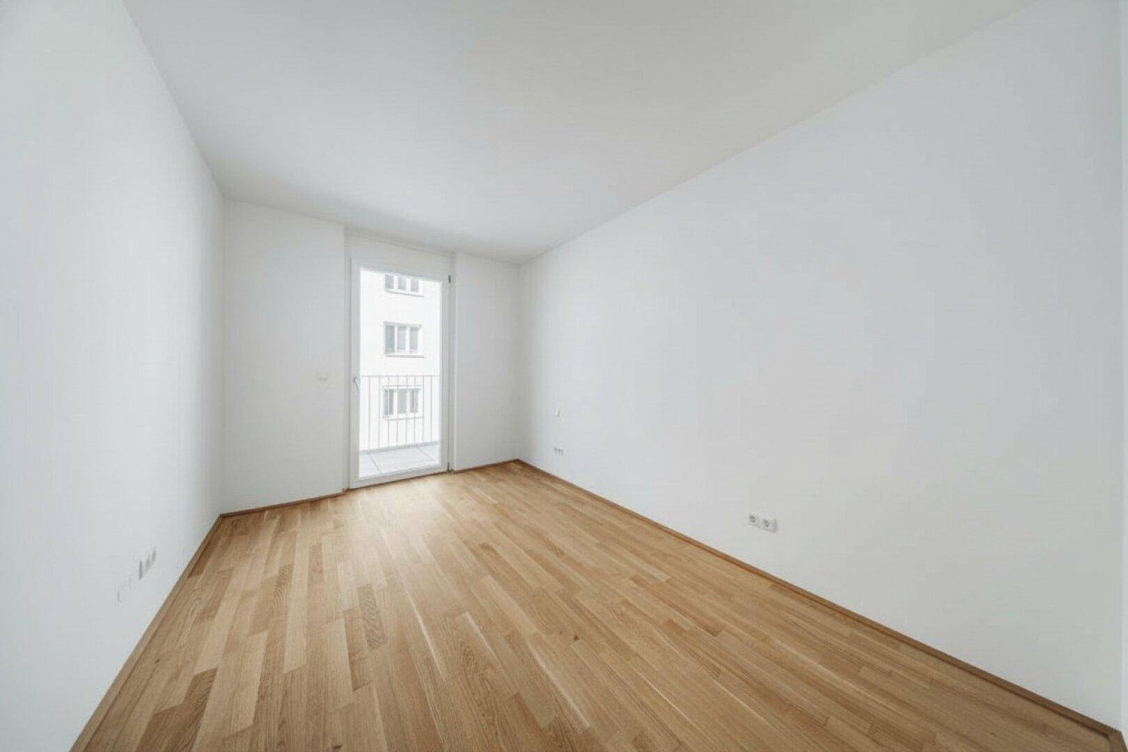 Kleinerer Raum mit Parkettboden und Zugang zu einem französischen Balkon, ideal als Schlafzimmer.