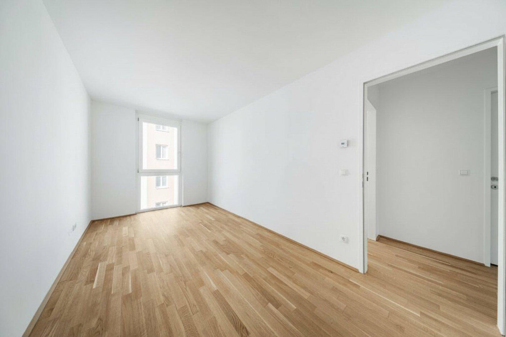 Heller Raum mit Parkettboden und einem Fenster, der sich gut als Schlaf- oder Arbeitszimmer eignet.