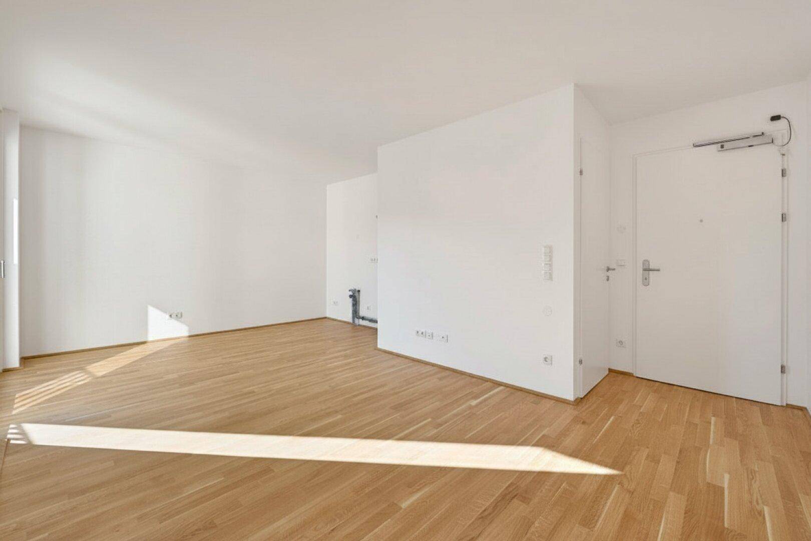 Heller, leerer Raum mit Holzboden und viel Tageslicht, bereit zur individuellen Gestaltung.