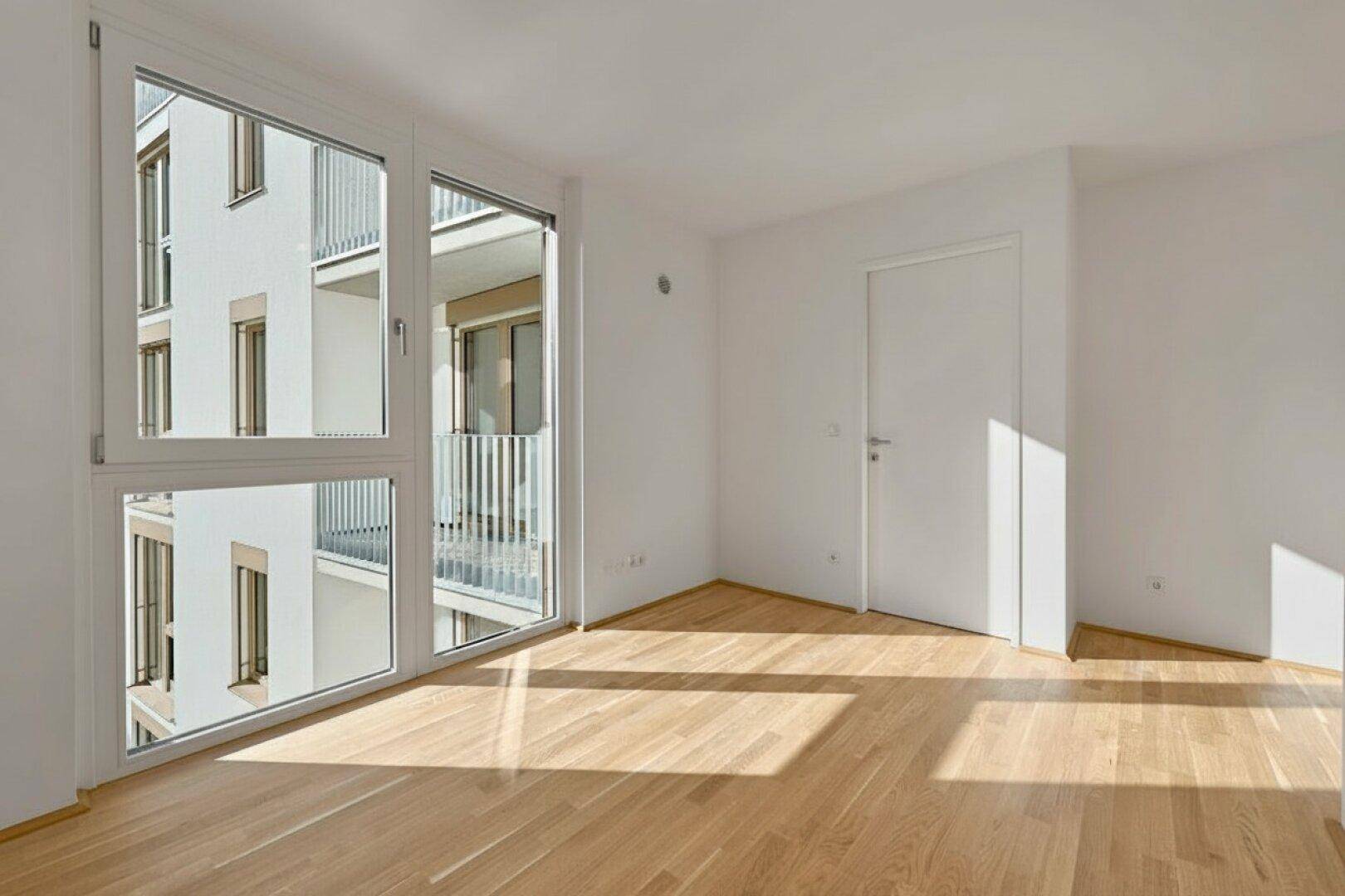 Leerer Raum mit großen Fenstern und Holzboden, bietet viel natürliches Licht und Ausblick.