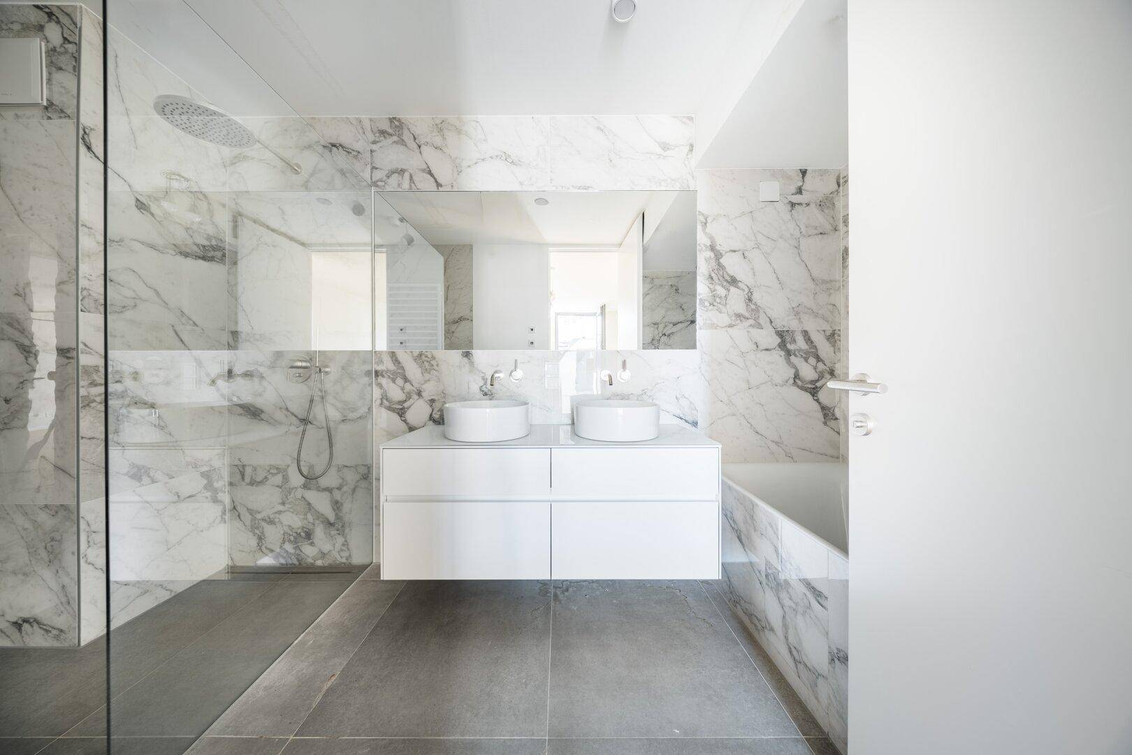 Modernes Badezimmer mit Marmorfliesen, Doppelwaschbecken und begehbarer Dusche.