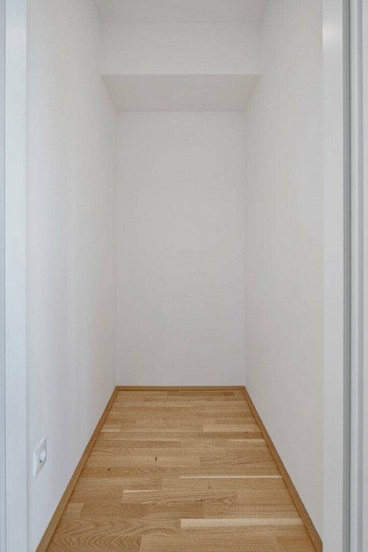 Kleiner, leerer Abstellraum mit Parkettboden und weißen Wänden, bietet zusätzlichen Stauraum.