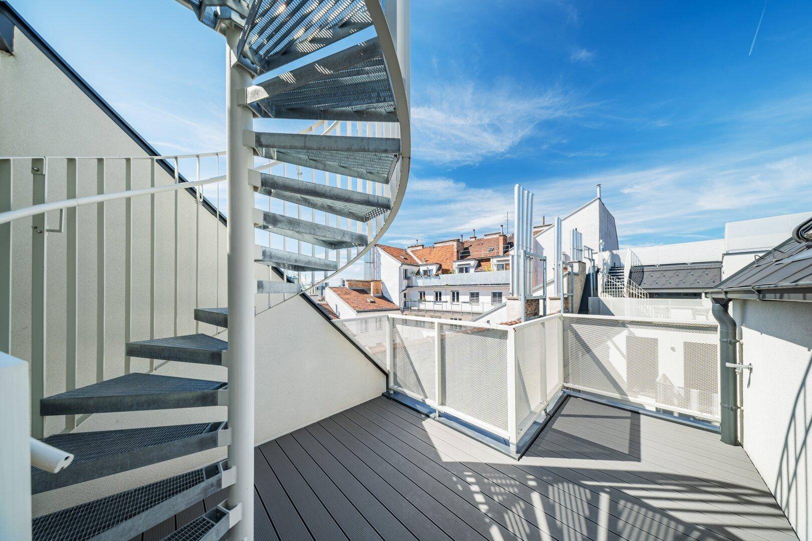 Dachterrasse mit Wendeltreppe und Holzdielenboden, bietet einen weiten Blick über die Dächer der Stadt.