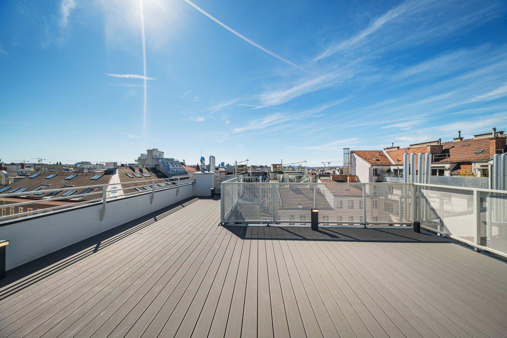 Weitläufige Dachterrasse mit modernem Geländer und Panoramablick über die städtische Skyline.