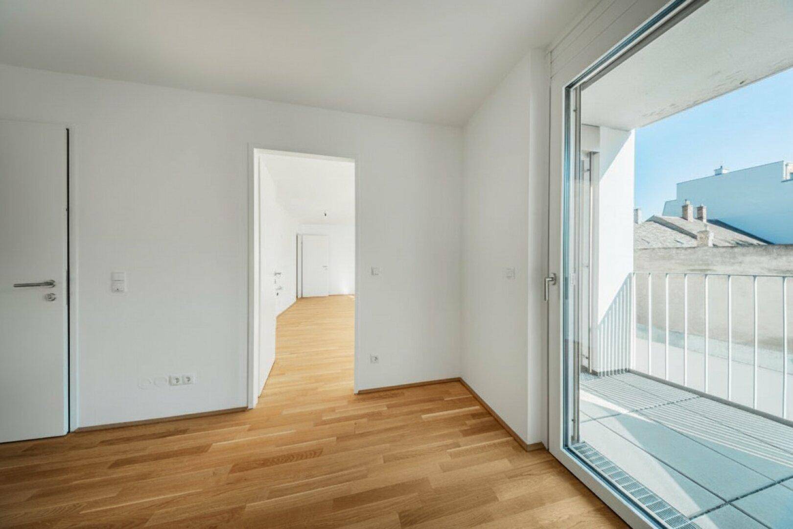 Leeres Zimmer mit Parkettboden und direktem Zugang zu einem Balkon, ideal für helle Wohnbereiche.