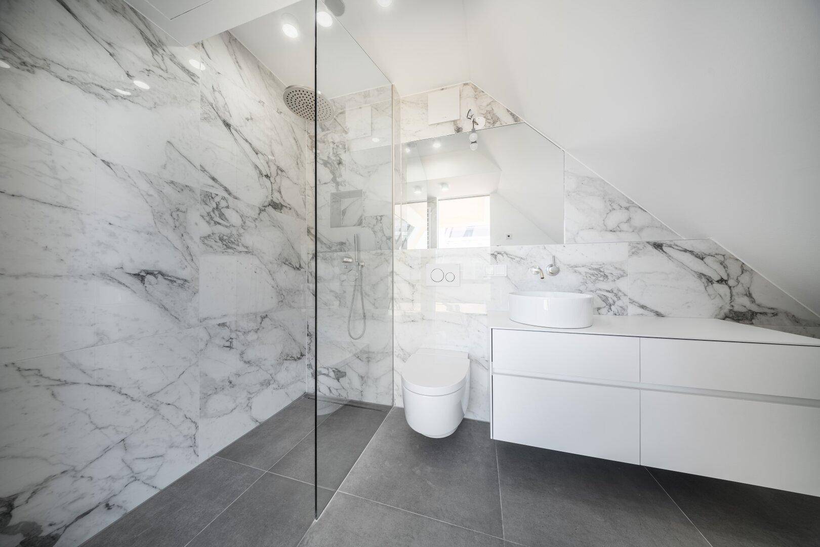Modernes Badezimmer mit Marmorfliesen, begehbarer Dusche und wandhängendem WC.