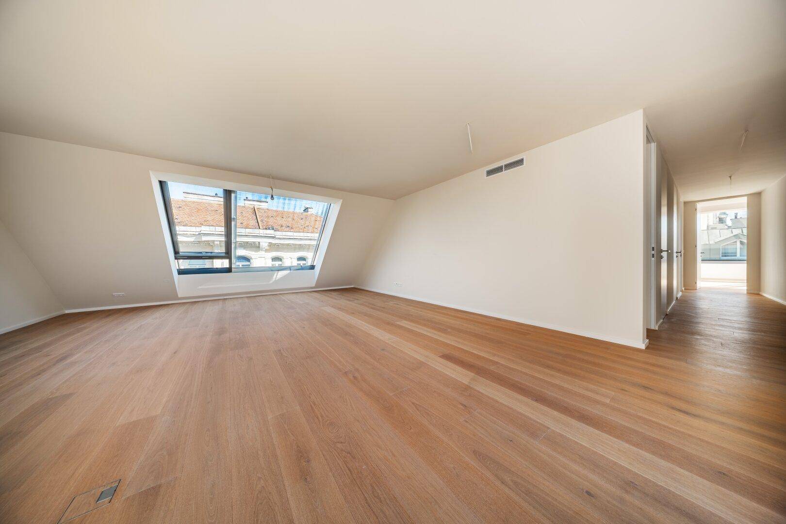 Heller Raum mit Holzboden und einem großen Dachfenster, das viel Tageslicht hereinlässt.