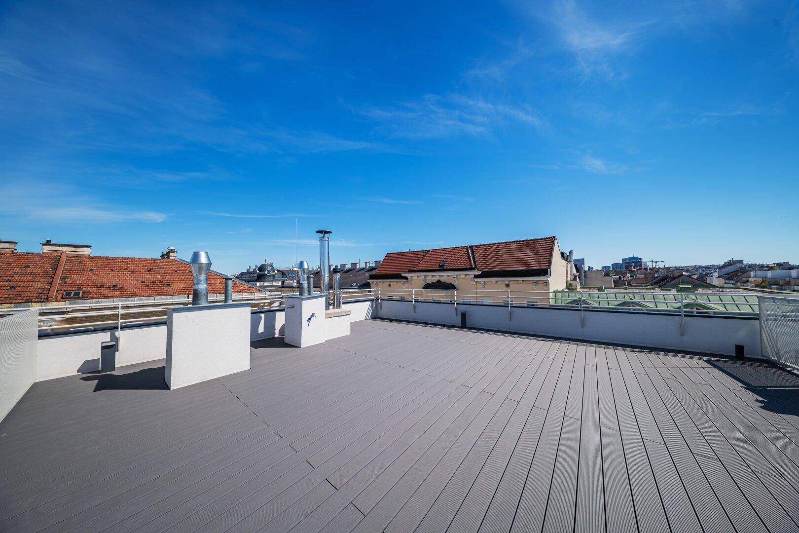 Weitläufige Dachterrasse mit Holzbelag und Panoramablick über die Stadt.
