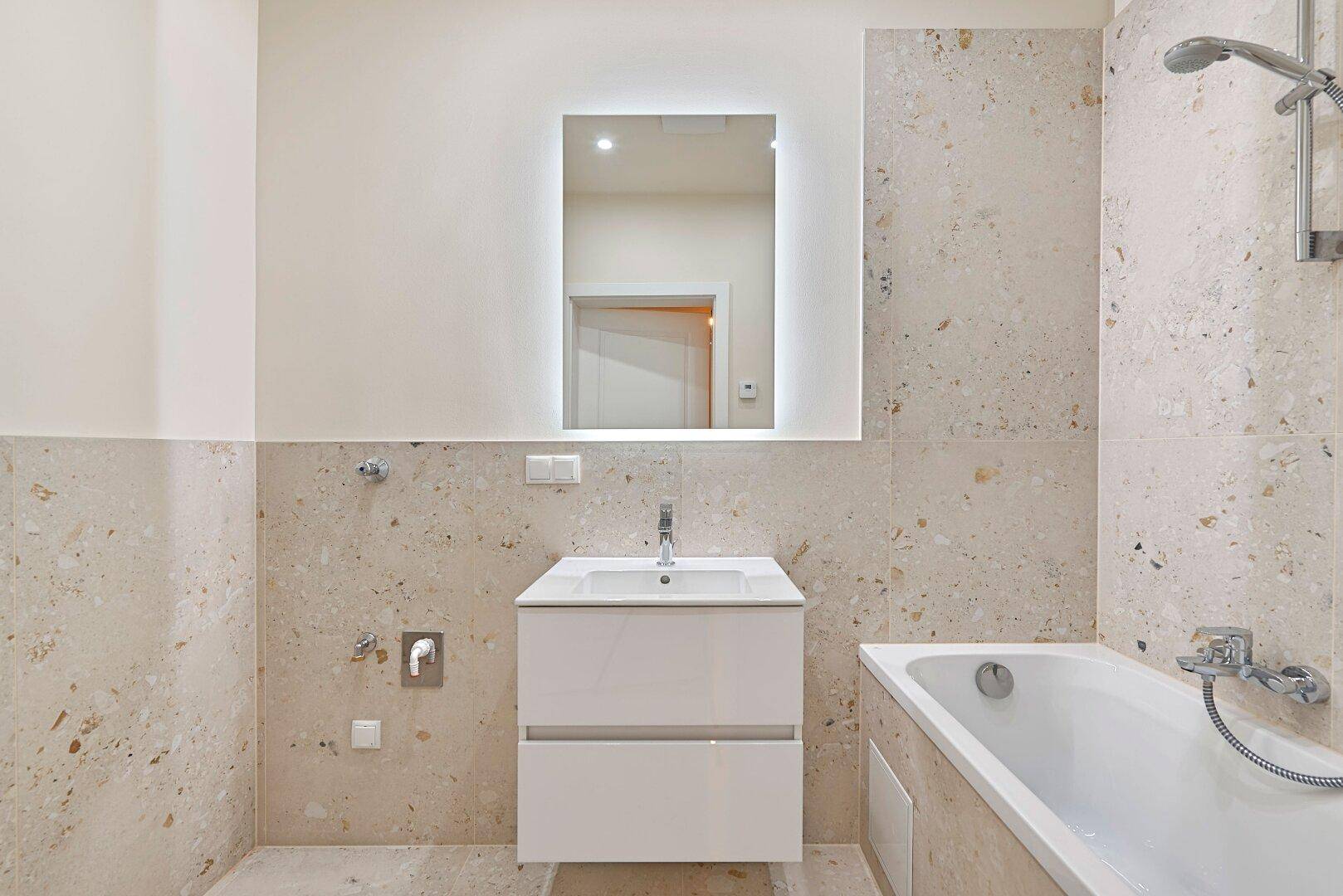 Modernes Badezimmer mit Badewanne, Einzelwaschbecken und hellen Fliesen.