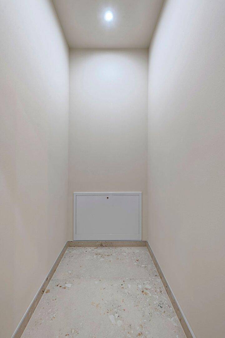Schmaler Abstellraum mit Fliesenboden und Zugang zu Versorgungseinrichtungen.