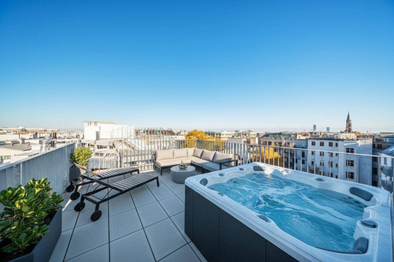 Exklusive Dachterrasse mit Whirlpool, Liegestühlen und Panoramablick über die Stadt.