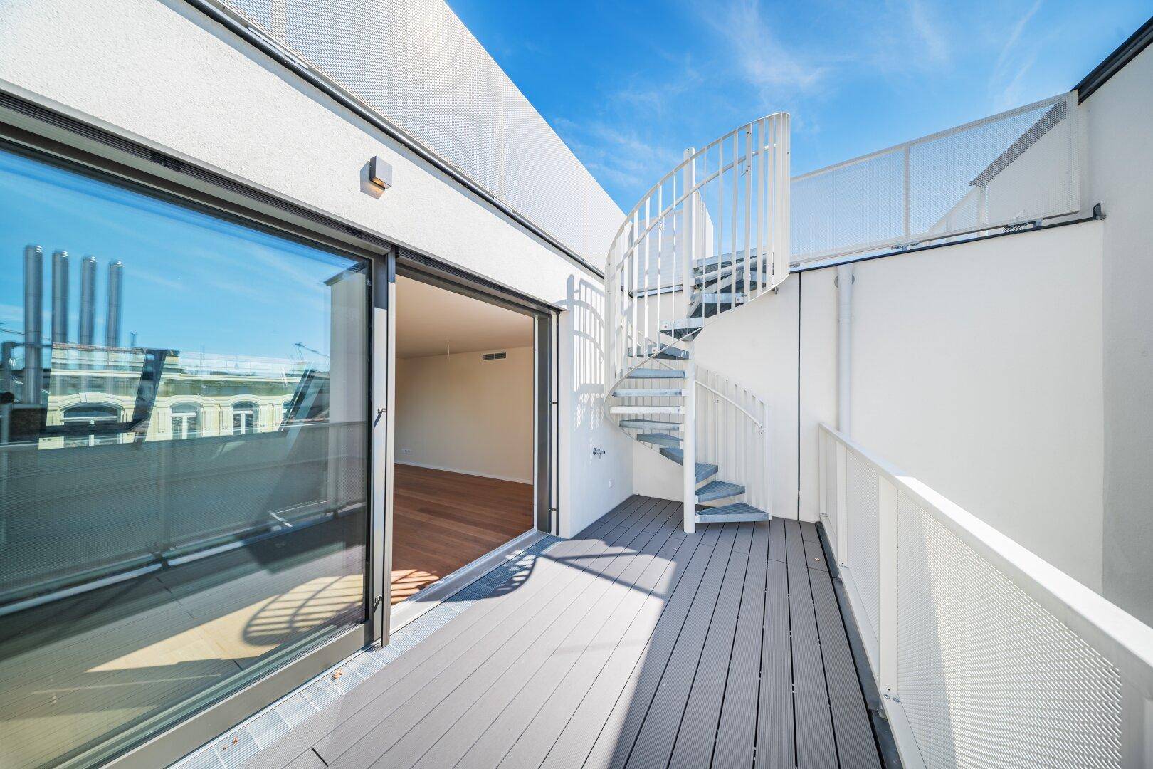 Große Dachterrasse mit Holzboden, Wendeltreppe und weitem Blick über die Stadt.