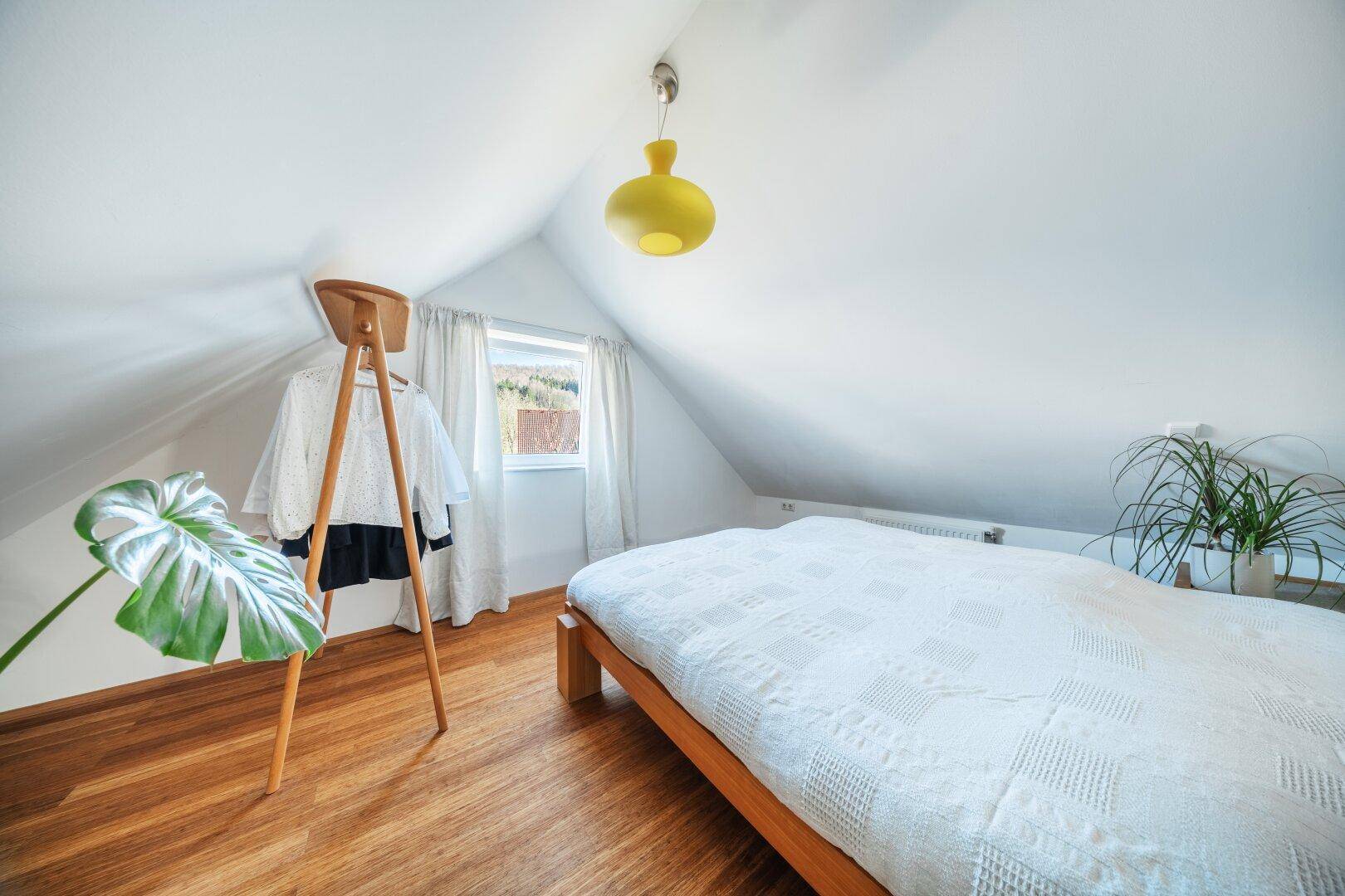 Gemütliches Schlafzimmer im Dachgeschoss mit Holzboden und schräger Decke.