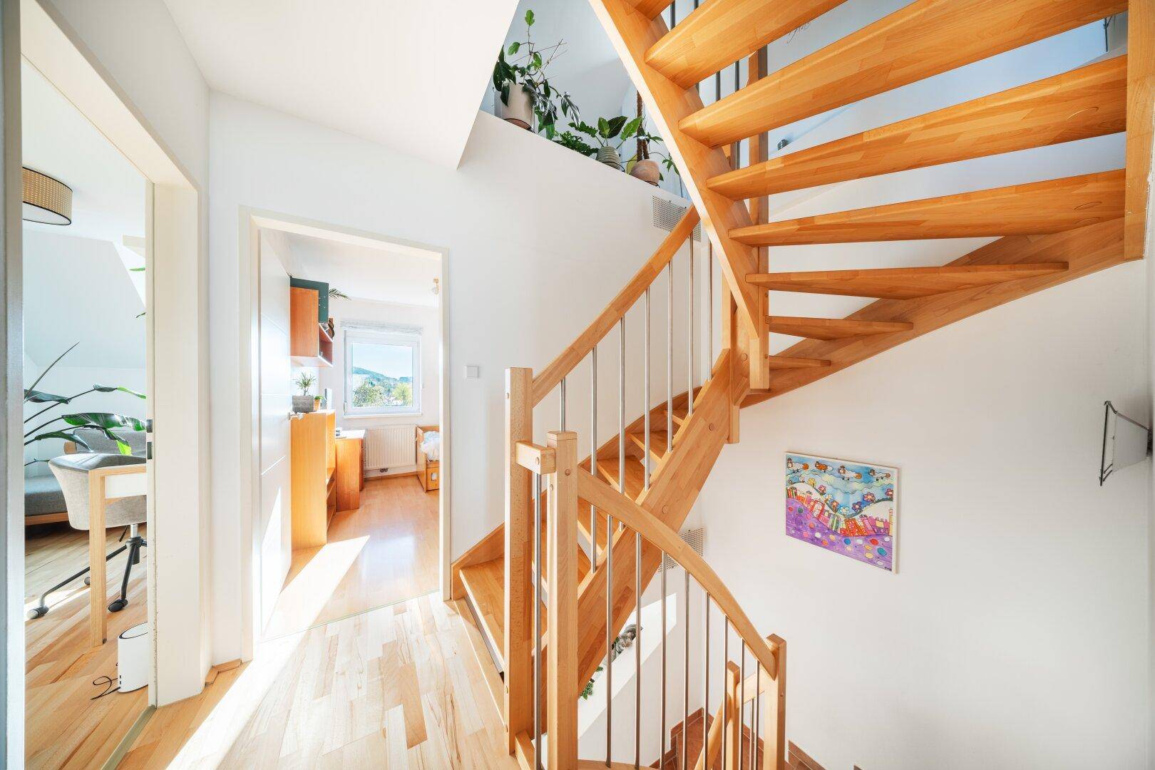 Heller Flur mit Holztreppe und Zugang zu weiteren Zimmern im Obergeschoss.