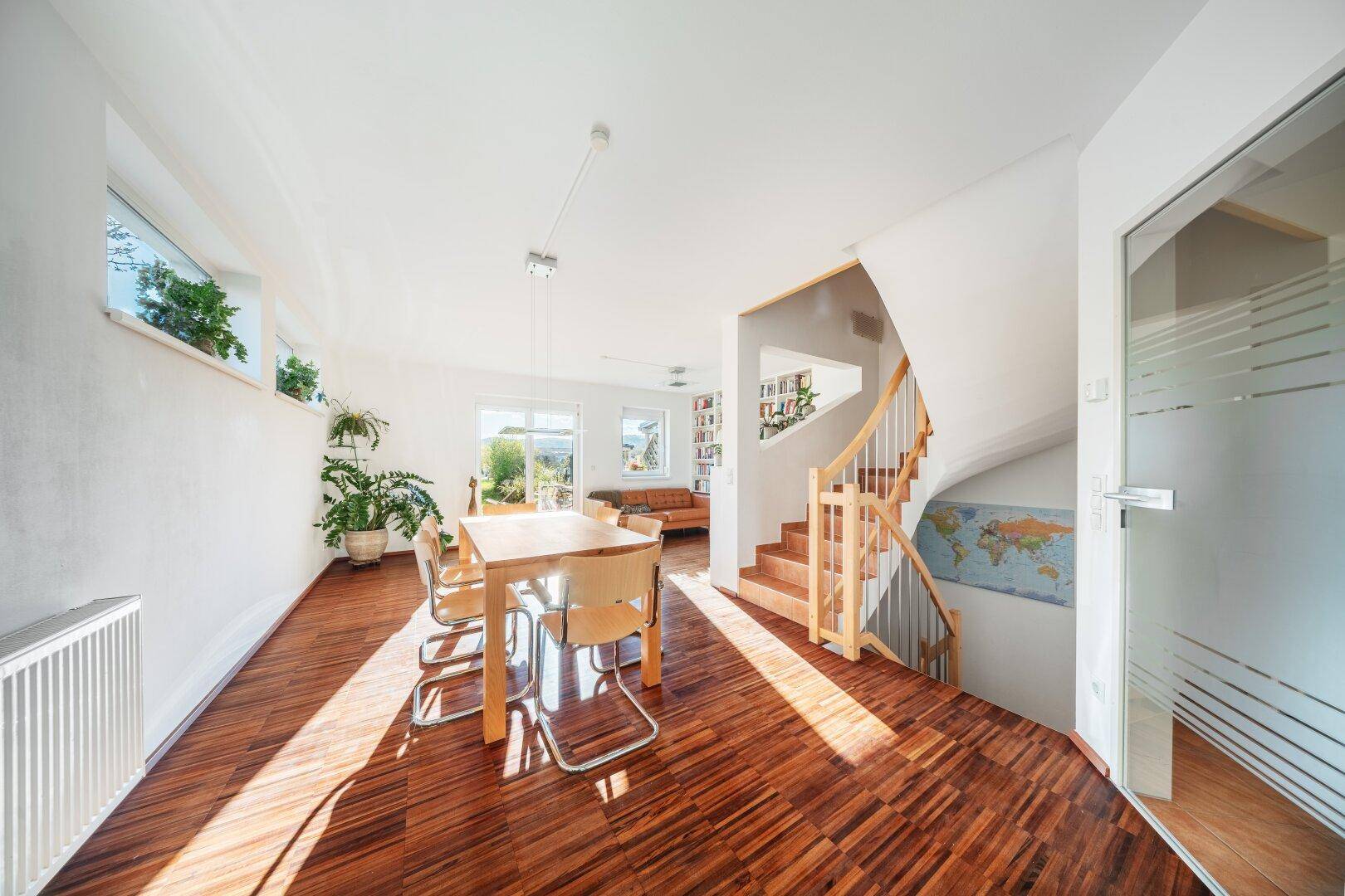 Geräumiger Wohn-Essbereich mit Holzparkett, Treppe und viel Tageslicht.