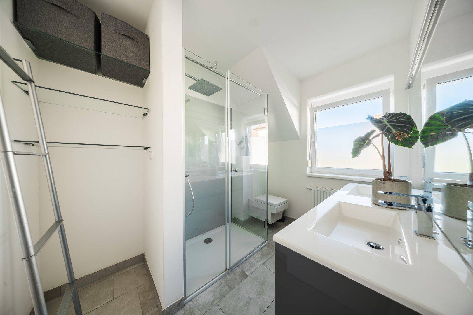 Modernes Badezimmer im Dachgeschoss mit Dusche, Doppelwaschbecken und Fenster.