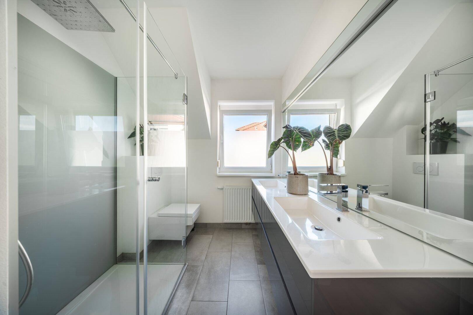 Helles Badezimmer mit großer Dusche, Doppelwaschbecken und Spiegelfront.