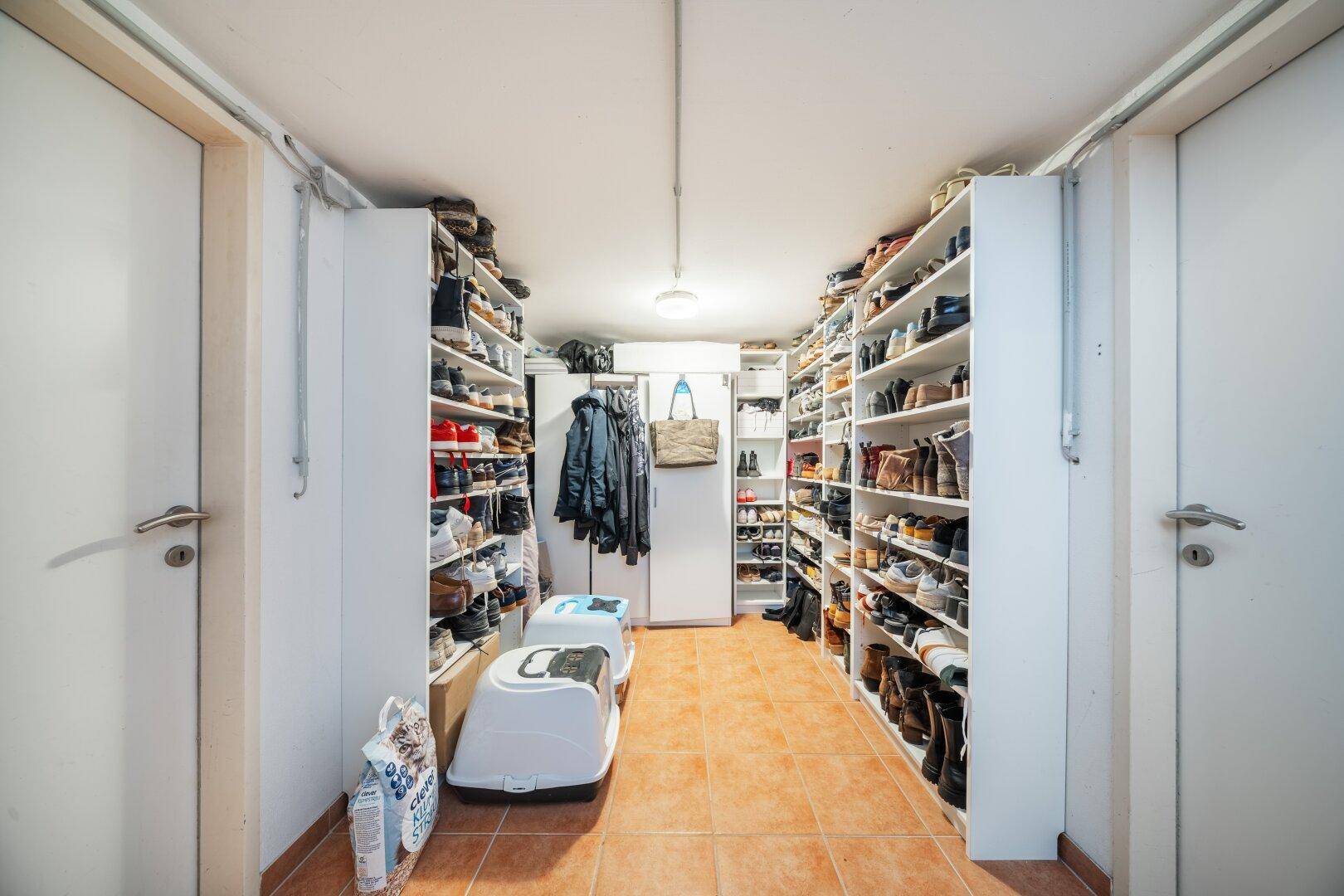 Praktischer Abstellraum mit zahlreichen Schuhregalen und viel Stauraum für persönliche Gegenstände.