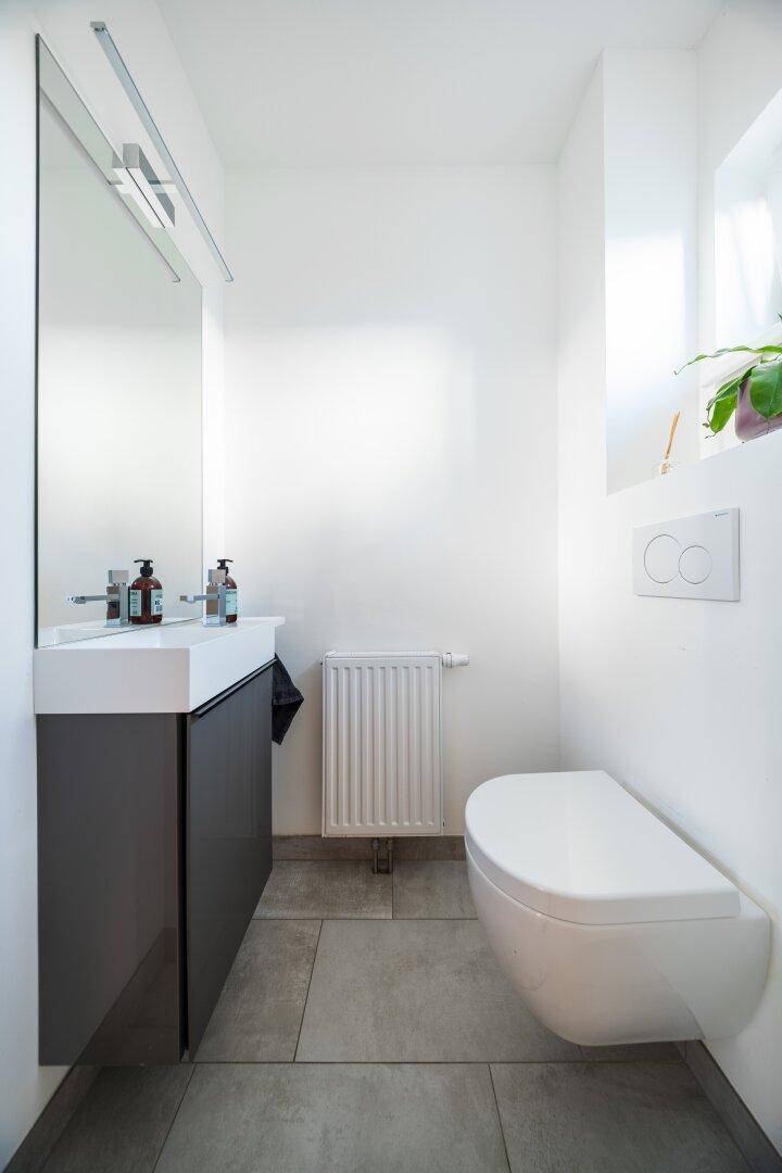 Modernes Gäste-WC mit wandhängendem WC und kleinem Waschbecken.