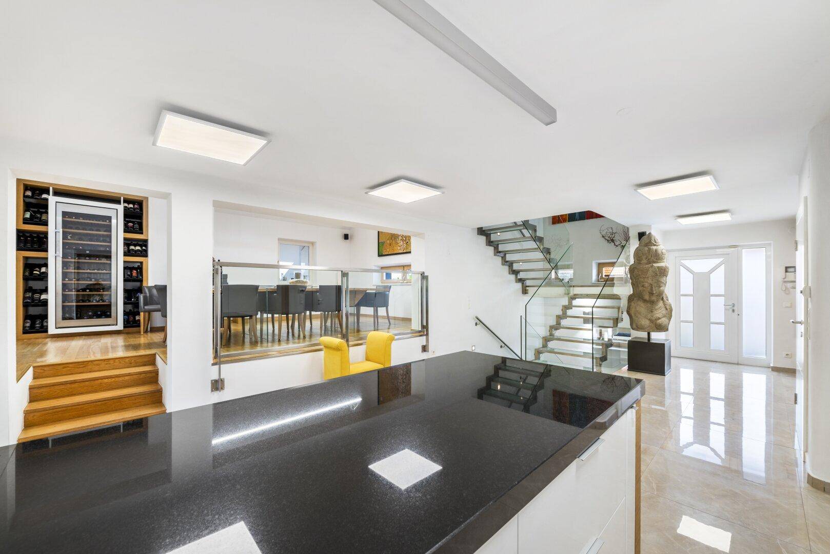 Heller Eingangsbereich mit glänzendem Boden, Weinkühlschrank und moderner Treppe.