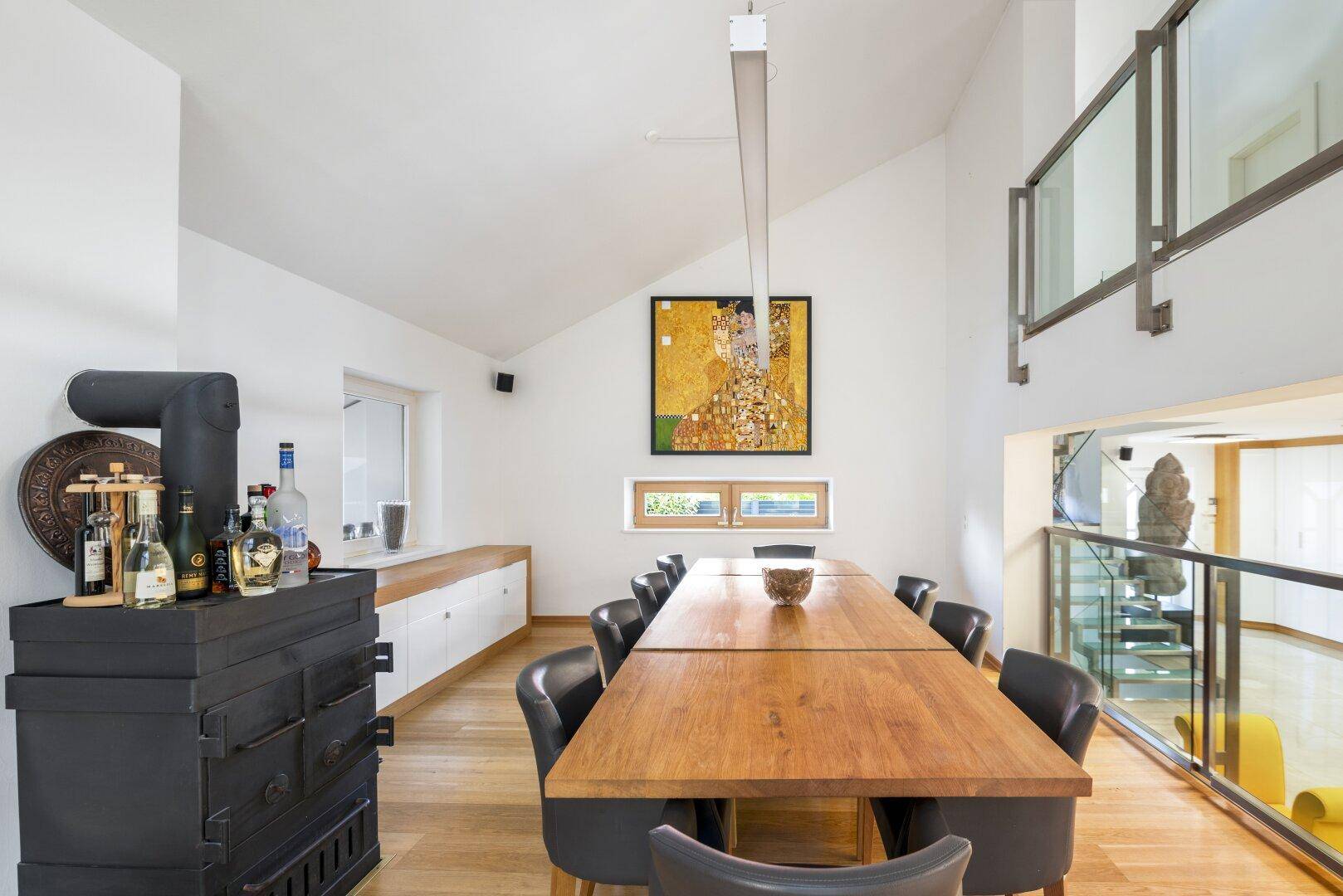 Eleganter Essbereich mit Holztisch, Kunstwerk und traditionellem Kachelofen.