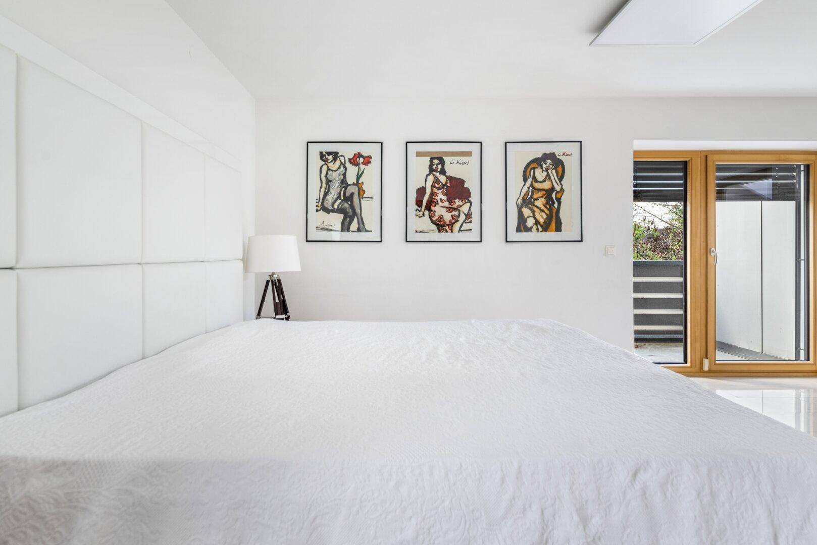 Helles Schlafzimmer mit großem Bett, moderner Dekoration und Balkonzugang.