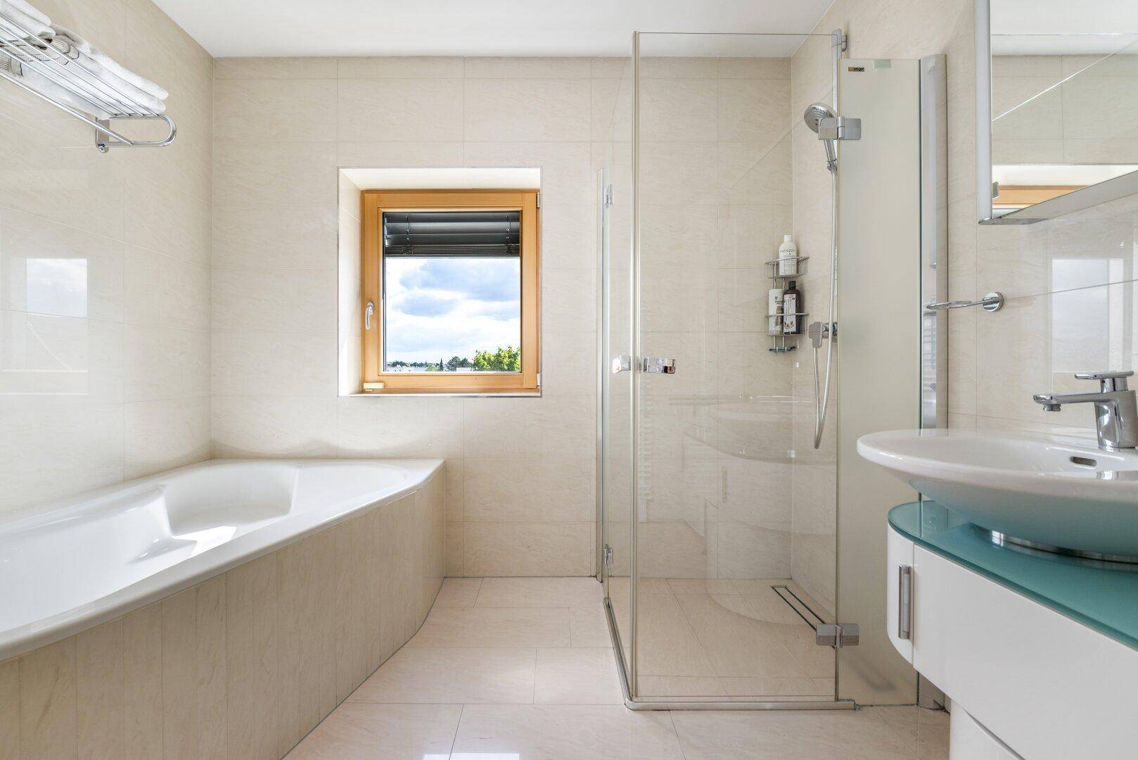 Modernes Badezimmer mit Badewanne, Duschkabine, Einzelwaschbecken und Fenster.