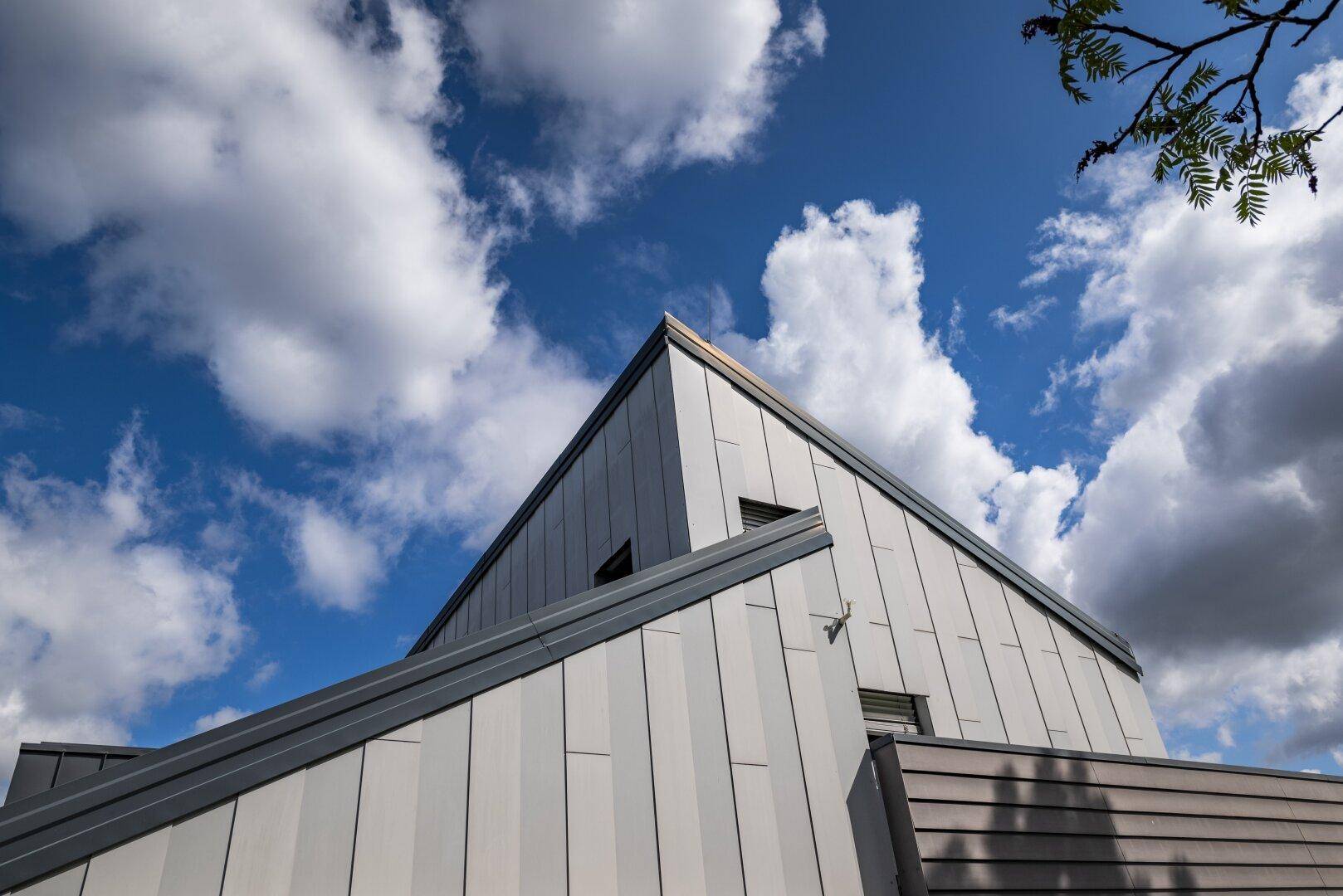 Moderne Architektur des Gebäudes mit markanter Dachlinie und Fassade unter blauem Himmel.