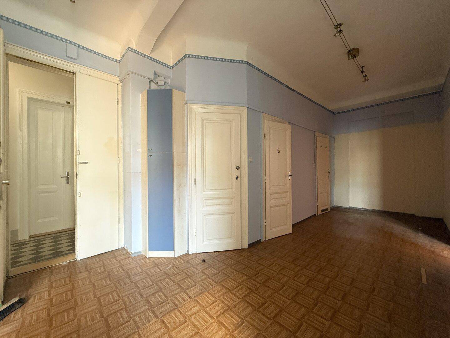 Geräumiger Flur mit Holzboden, blauen Wänden und mehreren Türen zu angrenzenden Räumen.